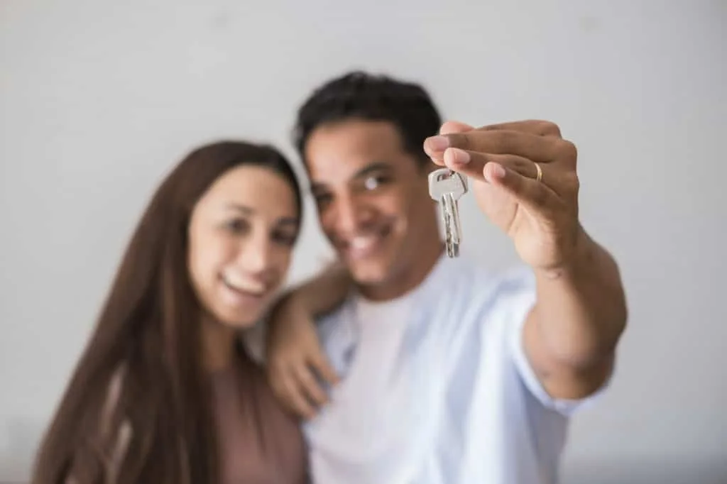 Close up of new home keys and young interracial couple smile and show the property - new life