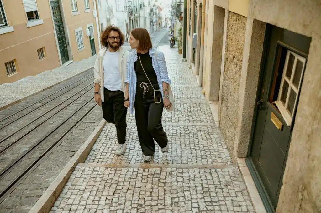 Beautiful hipster couple in love walking on old city street in Lisbon in a good