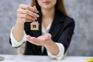 Image of a home sales woman holding key house. Real estate trading concept.