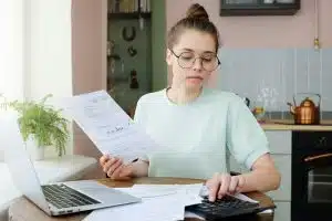 Young beautiful woman budgeting, managing utilities expenses, writing financial plan