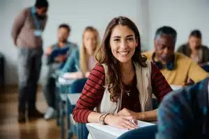 Happy female student learning in the classroom and looking at camera.