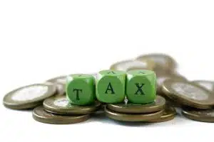 Wooden block with a TAX word on stack of coins