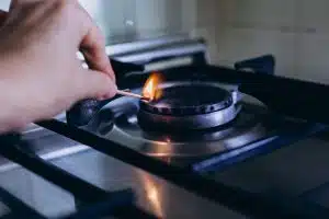 A woman's hand with matchstick lights gas stove in her apartment