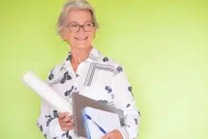 Confident expert architech teacher senior smiling woman with laptop and notebook in hand